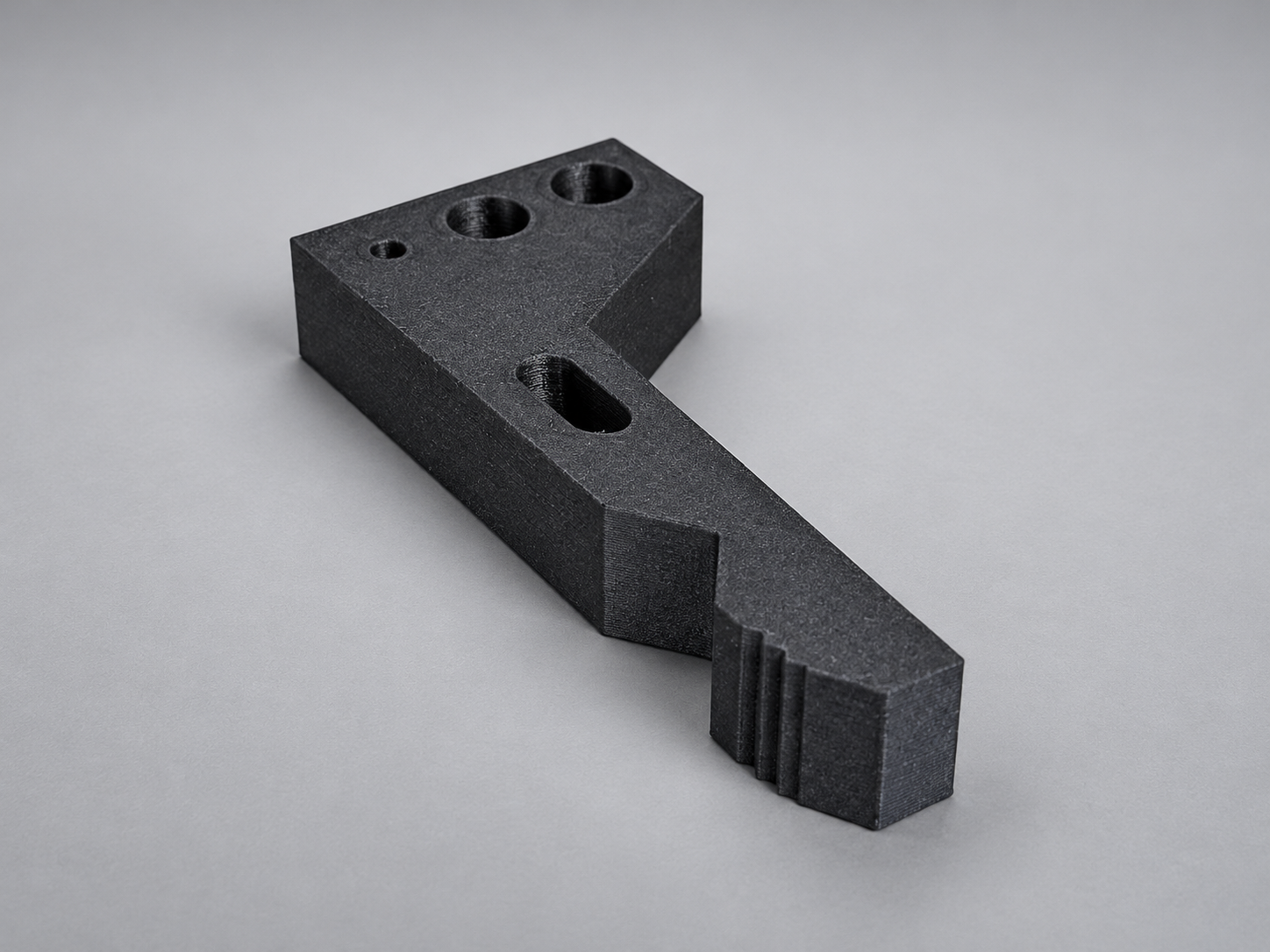 Black carbon fibre nylon 3D-printed gripper finger with mounting holes